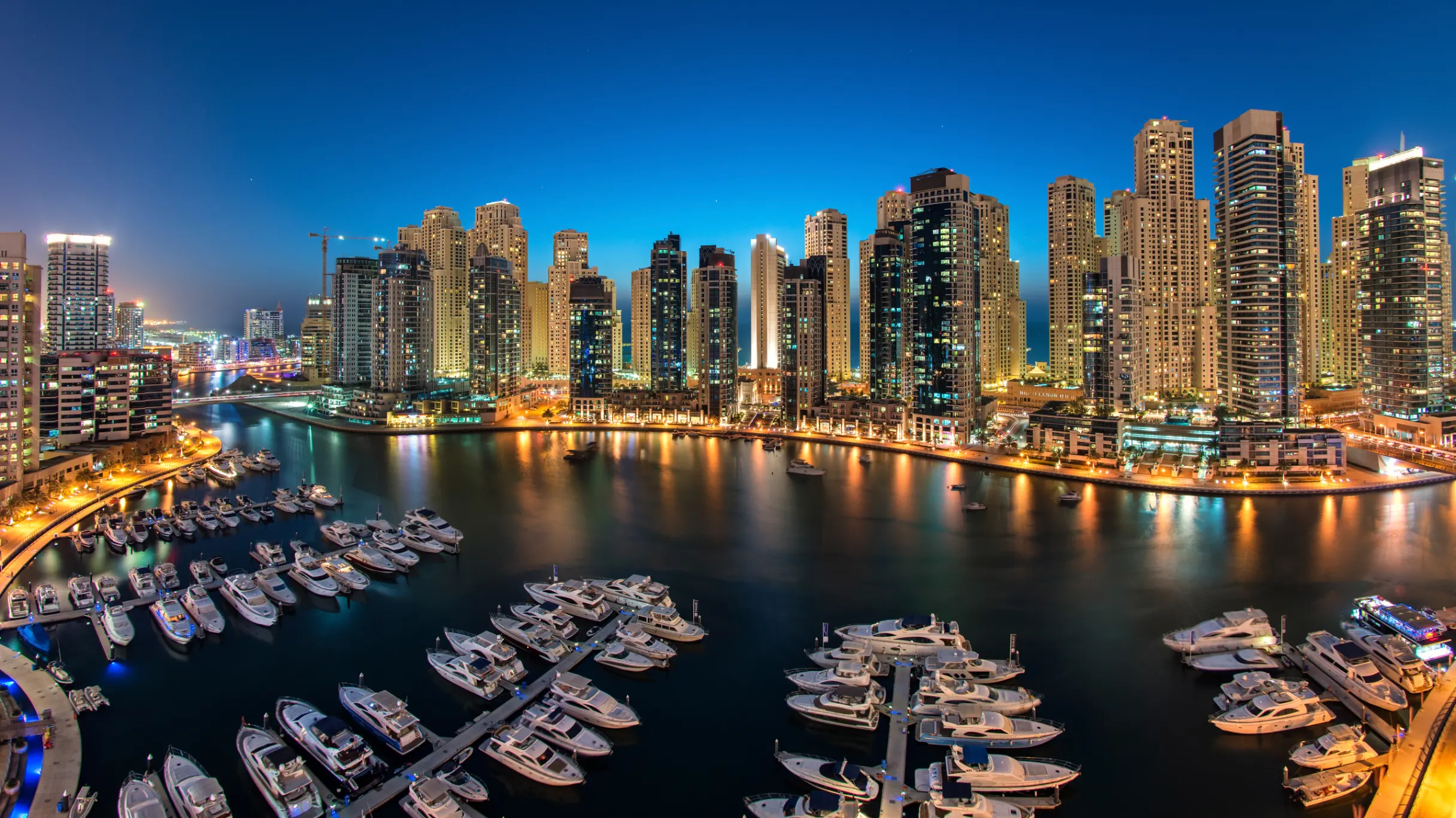 evening view across dubai marina with moored boats and tall buildings in the background